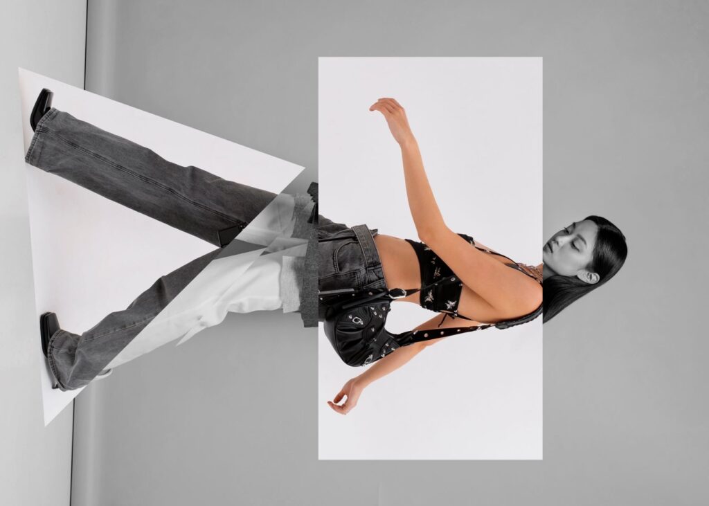 A stylish woman poses on a wall in a black and white photo, exuding elegance and confidence.