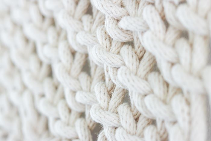 Close-up of a white knitted fabric highlighting the intricate patterns of knitwear.