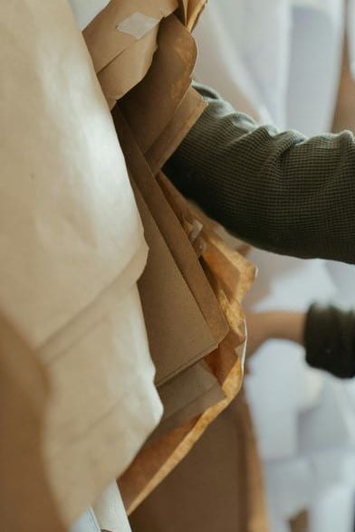 Close-up of a fashion designer's hand sorting through white and brown pattern papers for white label clothing design