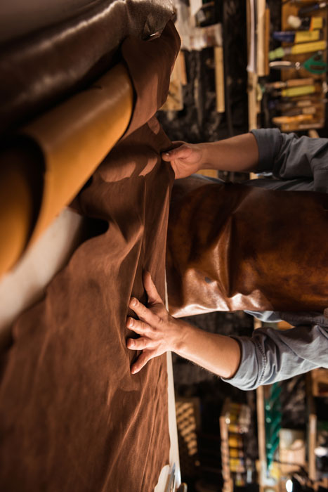 A skilled worker meticulously cutting fabric pieces from a large roll.