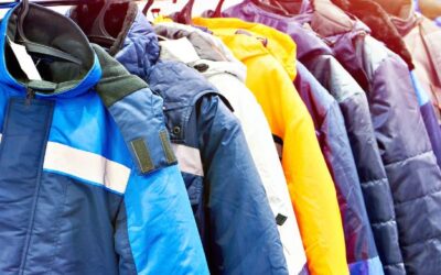 A variety of work jackets in different colors and styles hanging on a rack.