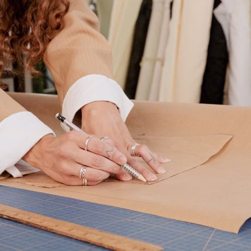 Designer creating clothing patterns on paper.